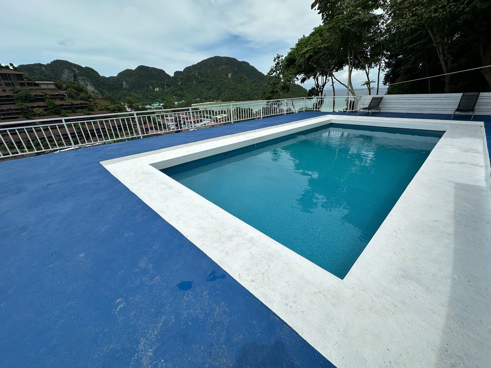 After: the same hillside pool with richer tile and deck blue and more saturated greens on the hills.