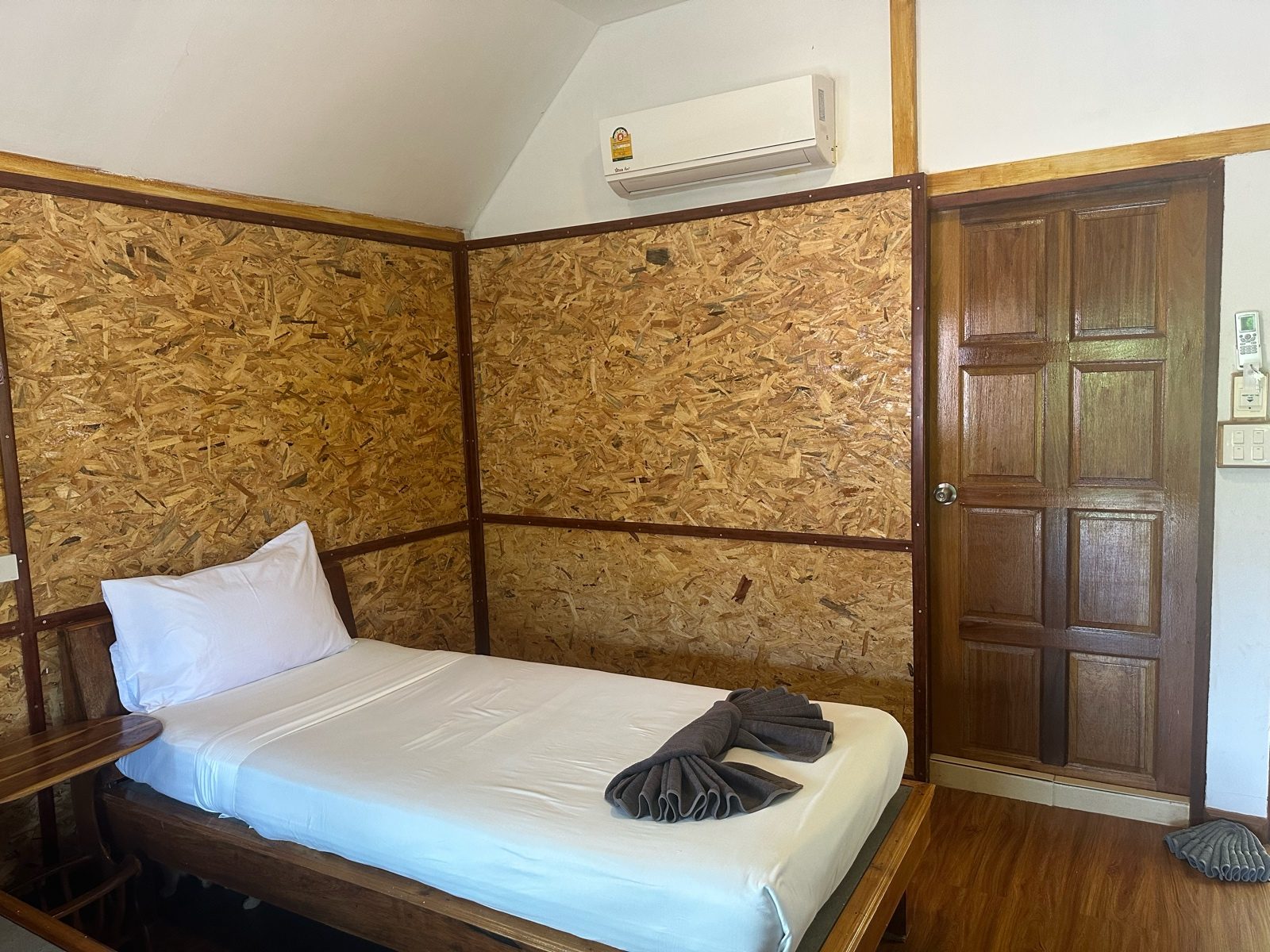 Before: a bedroom lined with wood panelling, the panels and the door reading dull and grey-brown.